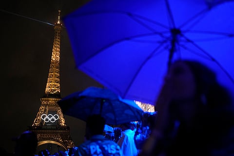 The Eiffel Tower is lit in the rain during the opening ceremony